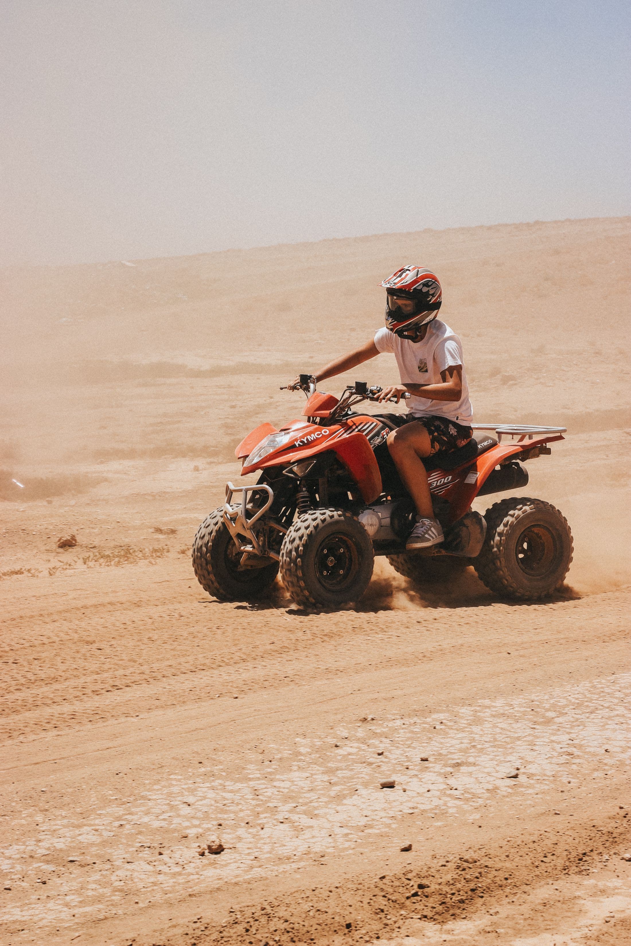 Helmeted quad rider crossing a dusty trail near Marrakech
