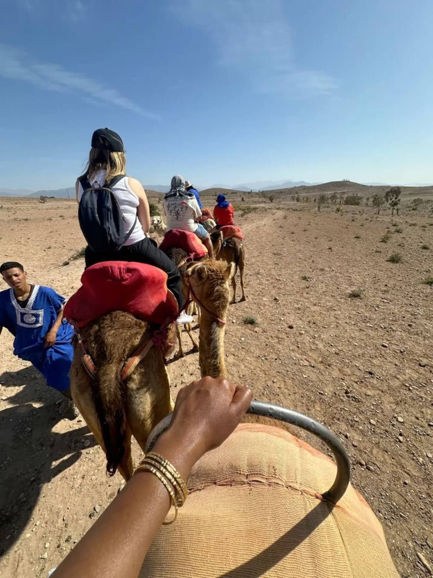 Guests riding camels through Agafay's rocky terrain